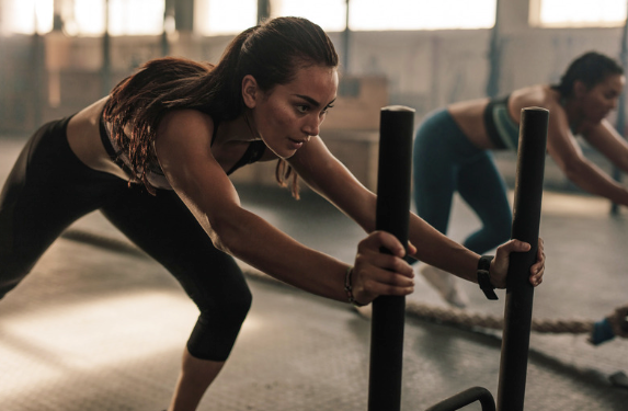 Female athlete performing sled push at the gym 